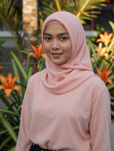 Nurul, 29-year-old Bruneian woman from Kuala Belait wearing soft pink hijab in garden setting